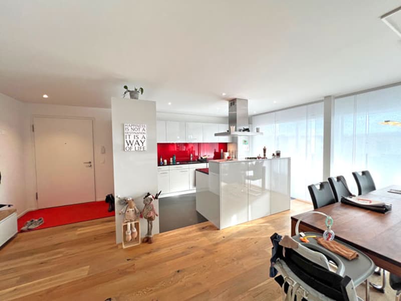 Open plan kitchen with modern appliances, kitchen island, dining table with chairs, hardwood floors, large windows