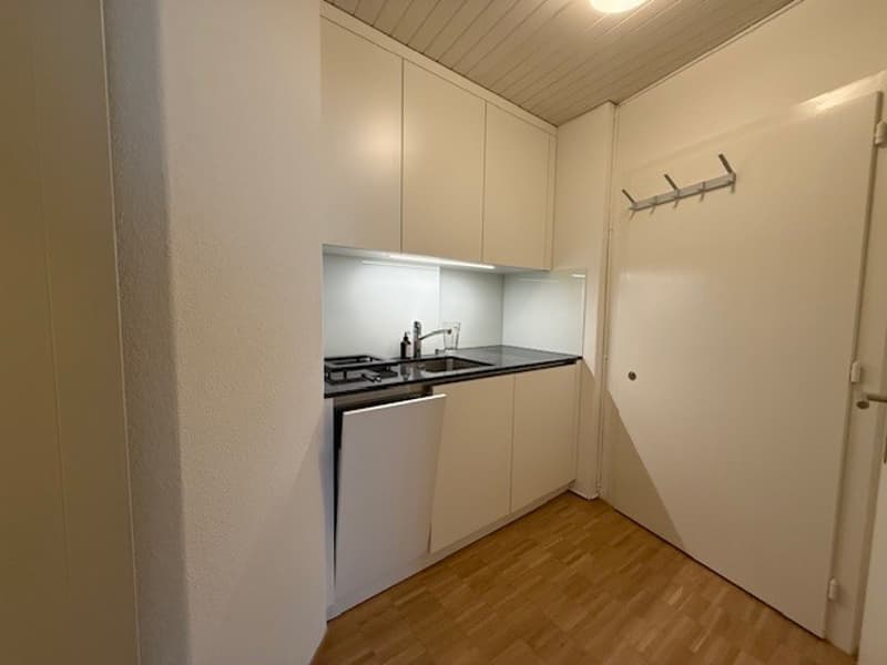 white cabinets, white floor, sink, gas stove, dishwasher, black countertop
