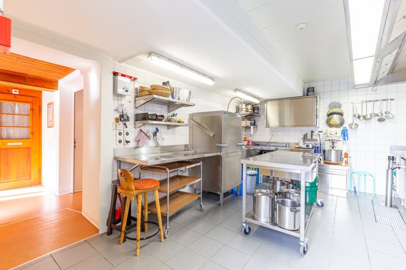 stainless steel counters, kitchen appliances, pots, pans, utensils, chairs, large open doorway