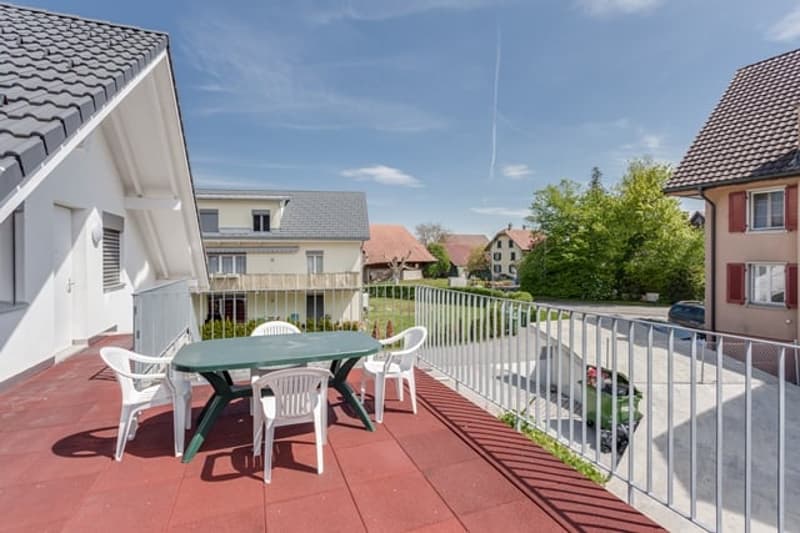 Balcony with table and chairs, metal railing, red floor