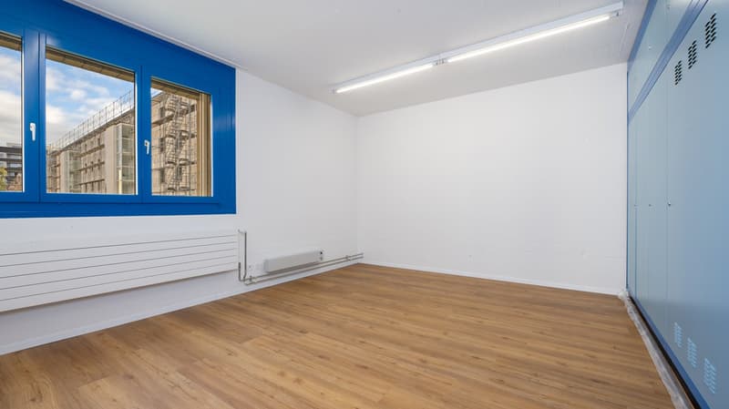 Large empty room, white walls, wooden floor, windows, no furniture