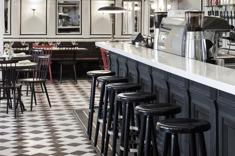 modern black and white checkered floor, wooden chairs, glass windows, large bar counter with a few stools, several lamps