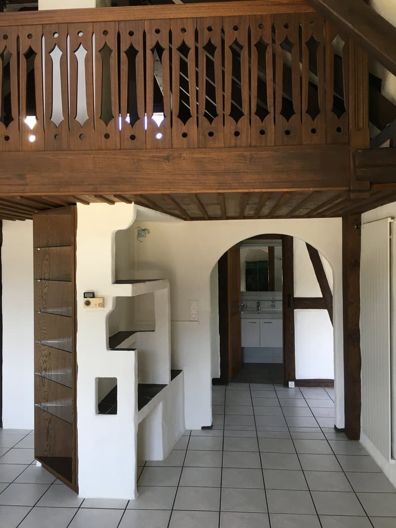 interior space with wooden railings, tiled floor, cabinets in the wall, and an open door leading to another room