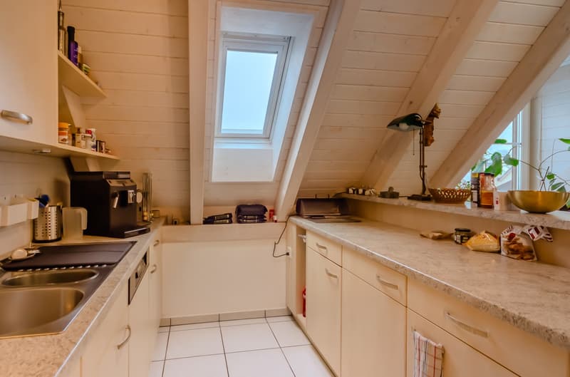 small kitchen with marble counter top, sink, stove, cabinet, dish washer, coffee maker, plant, skylight