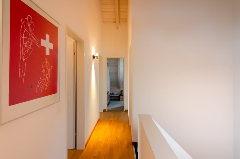 Corridor with wooden floor, white walls, light on the wall, open door to stairs