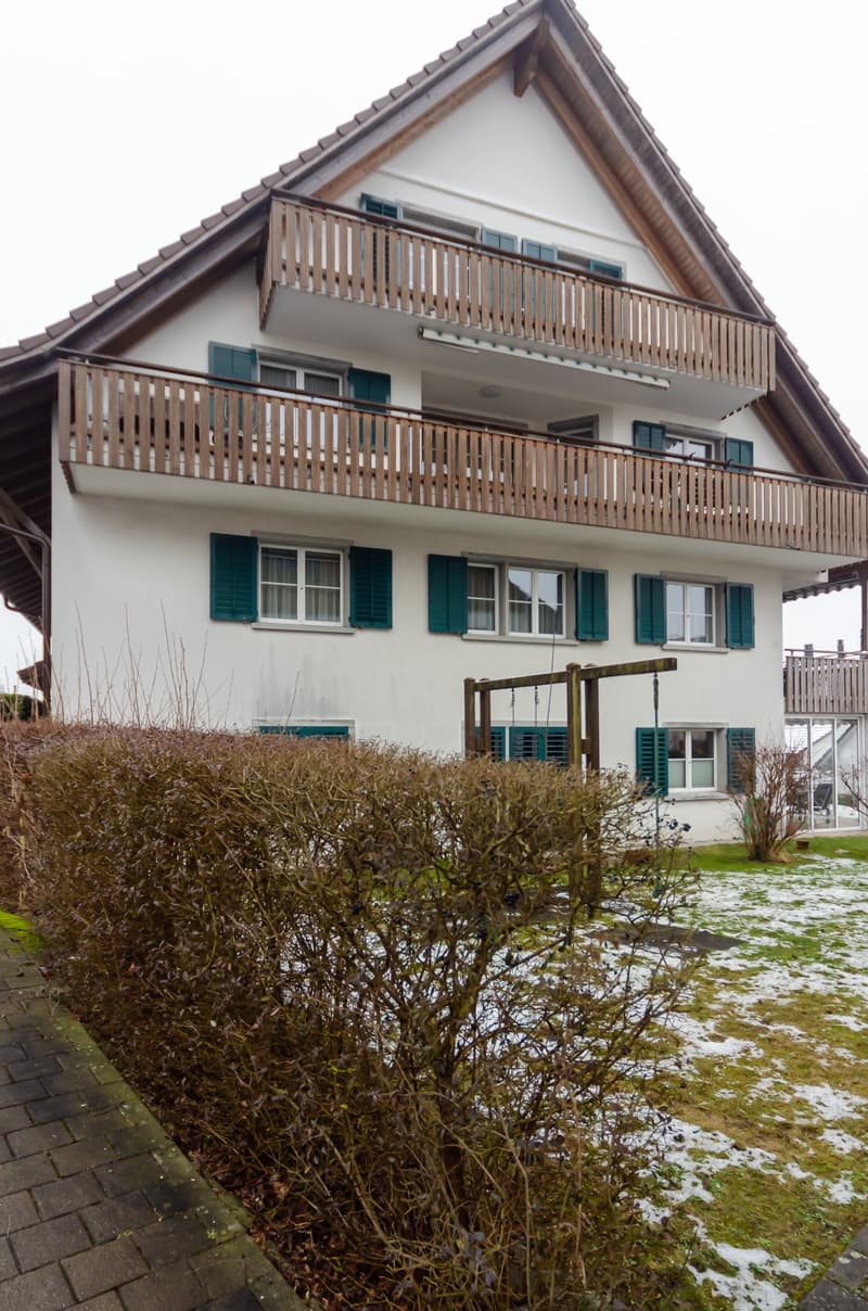 2-story house, white exterior, brown roof, green shutters, wooden balcony