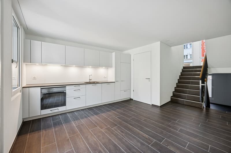 modern kitchen with white cabinets, tiled floor, stainless steel sink, built-in oven, and large window