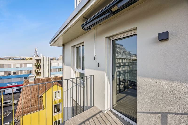 Apartment building exterior with balcony, modern design, grey walls, large windows, and metal railing