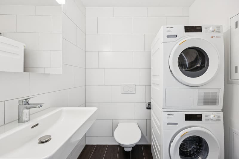 modern white tiles, white toilet, white vanity, white sinks, built-in washing machine, and dishwasher