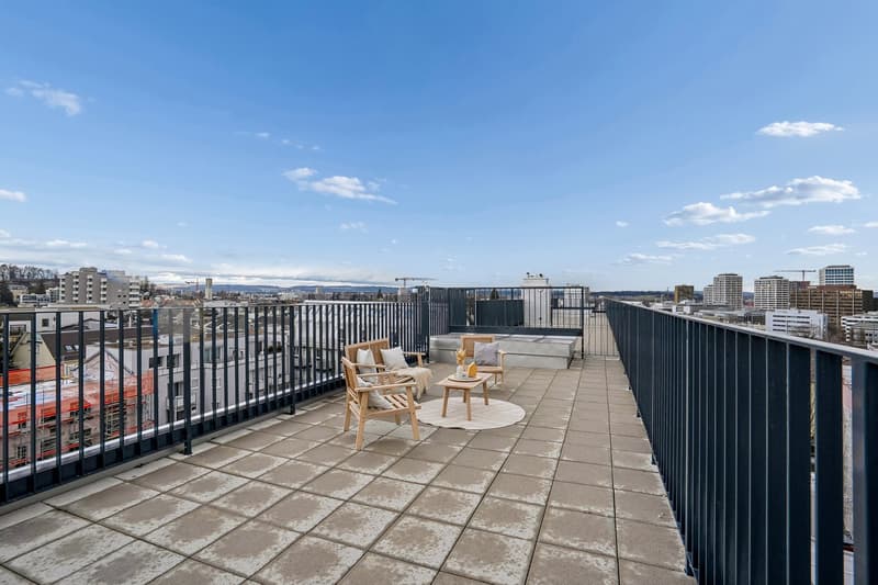 Modern design with two chairs, wooden coffee table, beige carpet, balustrade railing, open view, concrete floor