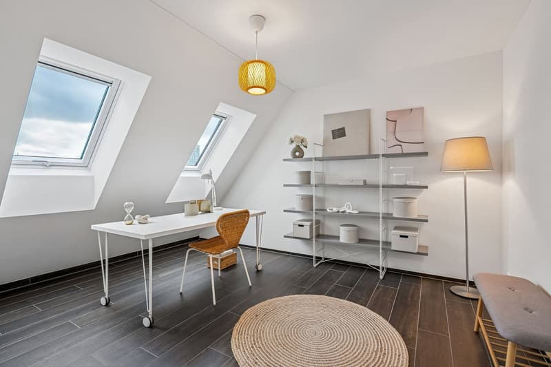 Desk with rolling chair, white shelves with various items, round rug, floor lamp, decorative items on desk, two windows