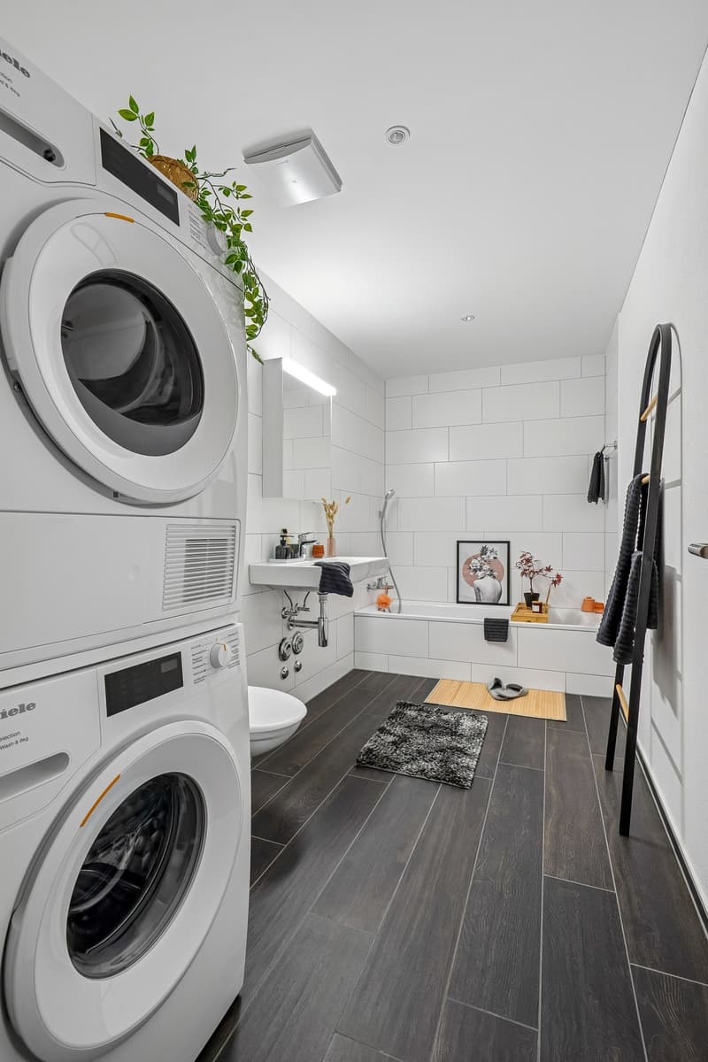 modern white tiles, white bathtub, under sink cabinet, two-in-one washer dryer, black and white floor mats