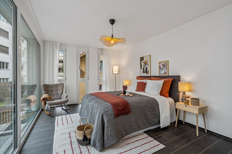 modern bedroom with wooden flooring, white walls, glass windows, large bed, bedside tables, night lamps, decorative items, chair, rug, balcony with rocking chair
