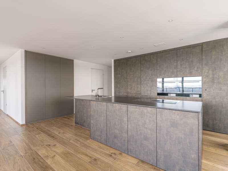 large kitchen island with countertops, modern cabinetry, wooden floors, built-in sink, stainless steel faucet, large oven