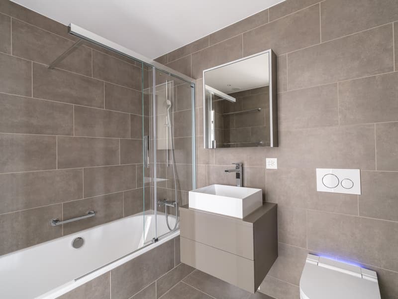 Bathroom with bathtub, glass shower, sink, and modern fixtures.