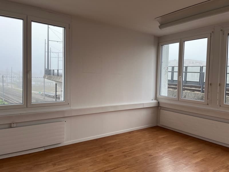 empty room, wooden floor, white walls, large windows, view of railway tracks