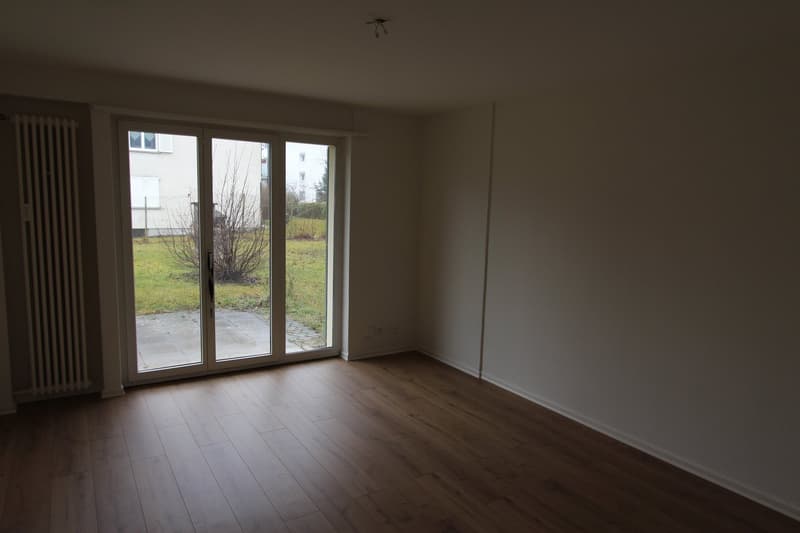 empty room, wooden floor, sliding glass doors, white walls, radiator, power outlets