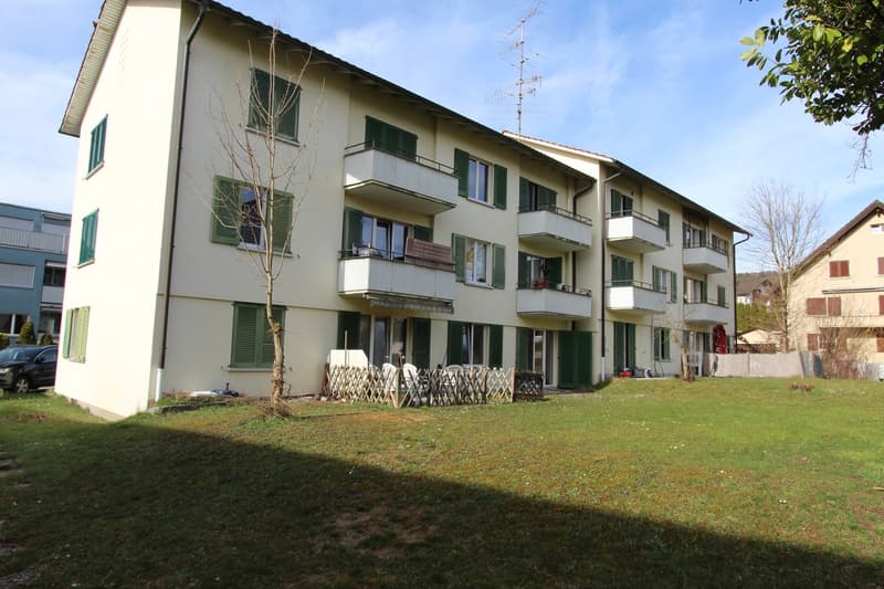 3 story building, white exterior, green shutters, balconies, fenced yard, car parked