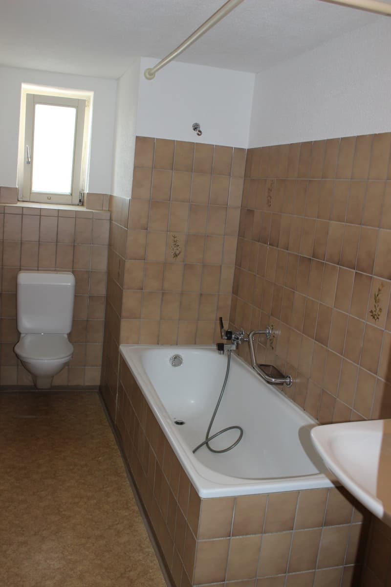 Bathroom with bathtub, sink, toilet, tiled walls, window
