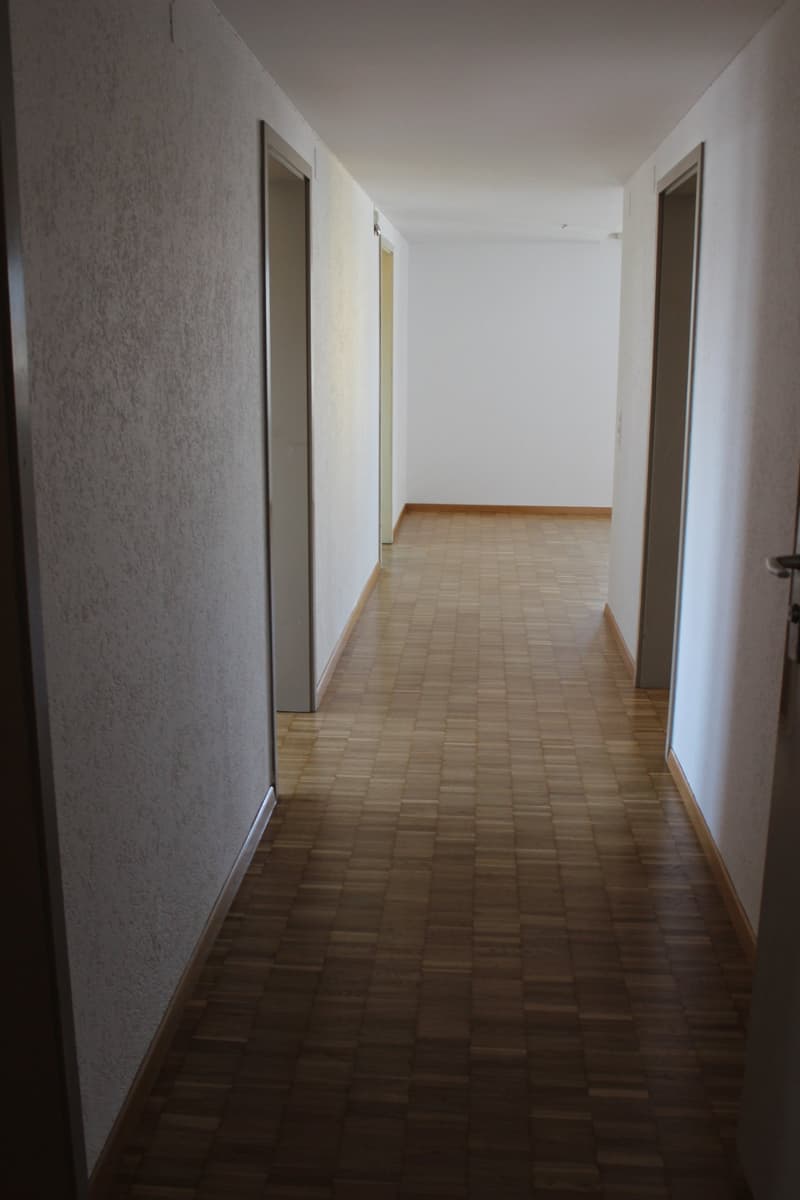 Empty hallway with wooden floor and white walls