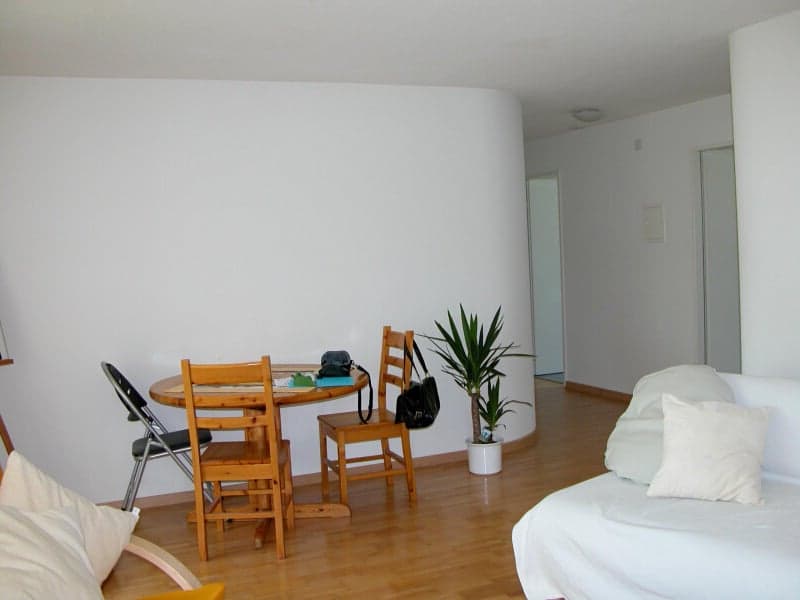 table with 4 chairs, couch, white walls, floor, potted plant