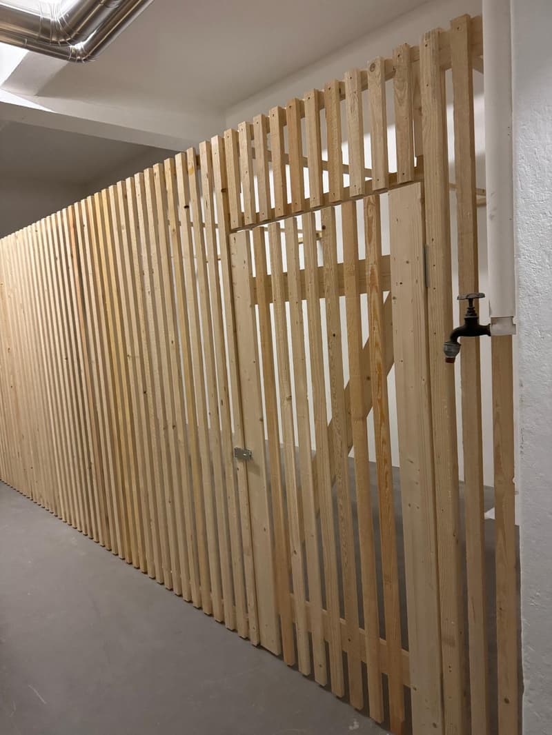 wooden fence, gray flooring, white walls, metal pipe, black pipe valve