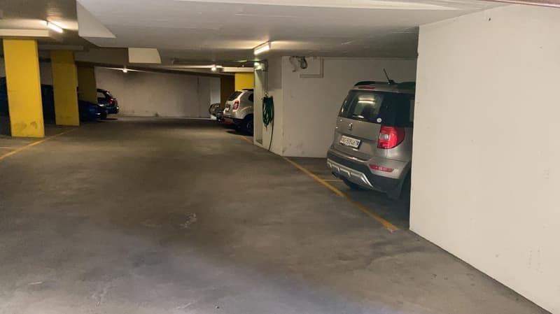 an empty car parking area with cars parked on both sides of the road