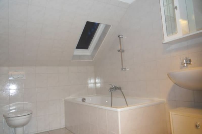 Bathroom with bathtub, toilet, sink, and a skylight window.