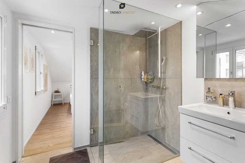 Das Bad überzeugt mit bodentiefer Dusche, klarem Design und einem praktischen Stauraum.