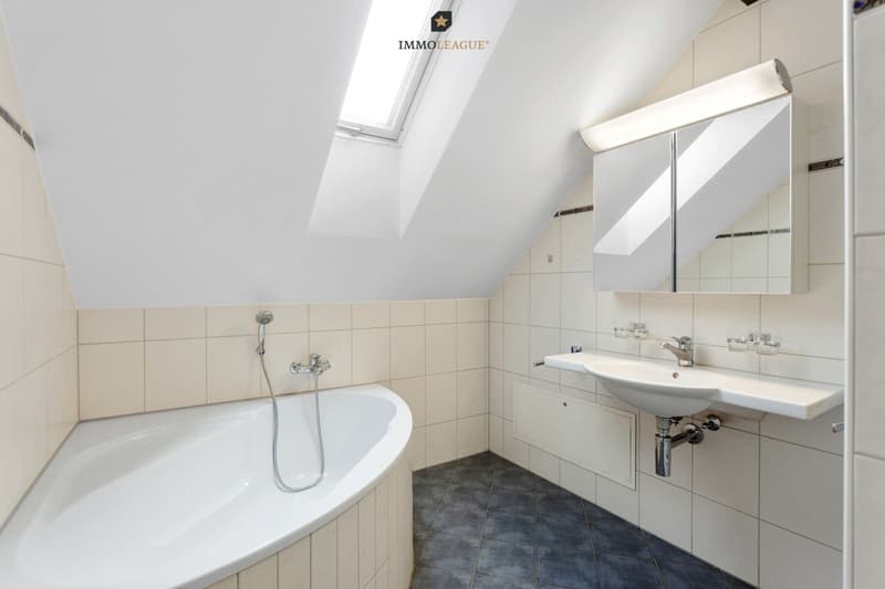 Vom Schlafzimmer aus betreten Sie das zeitlos elegante Bad mit Badewanne, Dusche und Dachfenster.