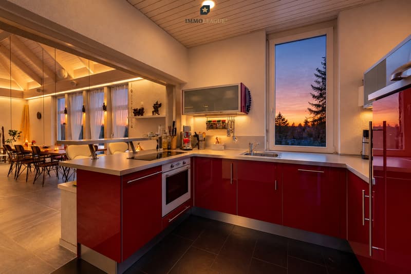 Moderne Designküche in elegantem Rot - stilvoll inszeniert im warmen Dämmerlicht.