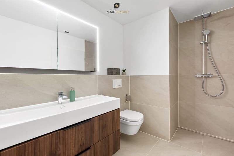 Elegante Badwelten: Hochwertige Materialien definieren das Ambiente im grossen Hauptbad mit Badewanne und Dusche sowie im separaten Gäste-WC.