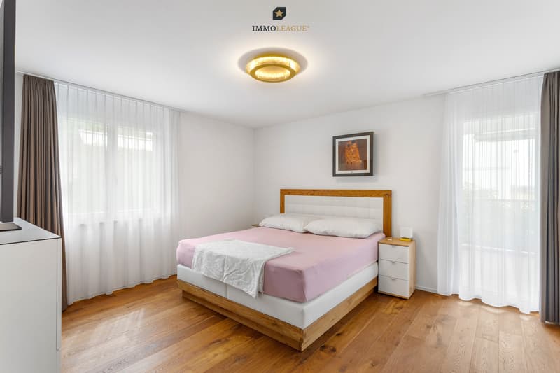 Das einladende Schlafzimmer mit hochwertigem Parkettboden verfügt über eine eigene Klimaanlage und bietet Zugang zum grossen, überdachten Balkon.