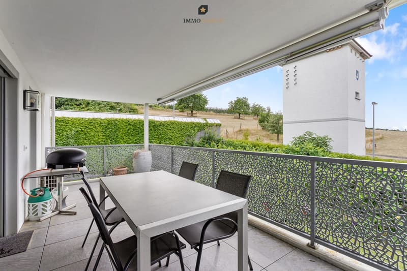 Der grosszügige, überdachte Balkon mit Sonnenstore bietet einen wunderschönen Blick ins Grüne und verfügt über ein praktisches Reduit für mehr Stauraum.