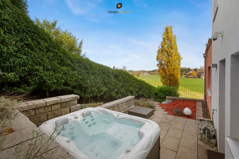Eine zusätzliche Terrasse mit Whirlpool liegt gegenüber.