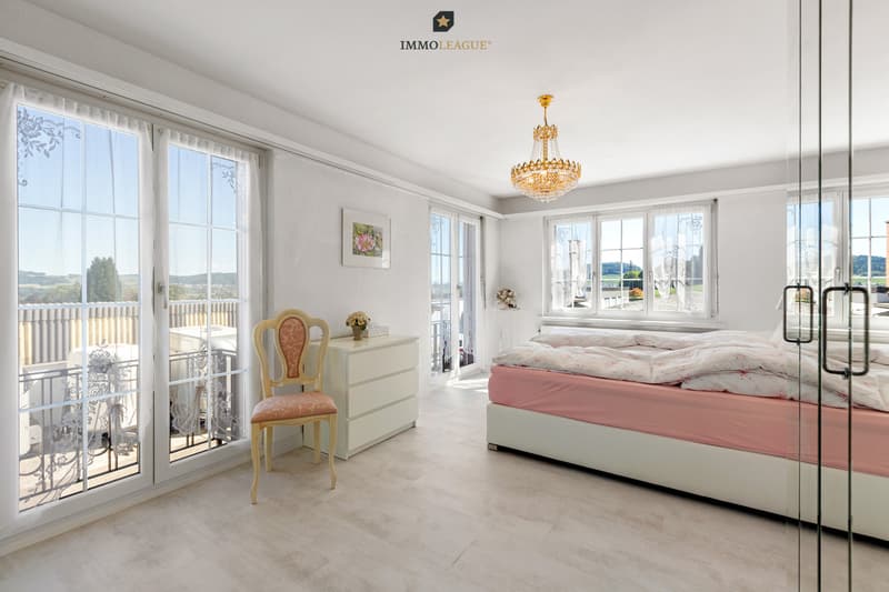 Grosszügige Fensterflächen, sanfte Farben und viel Licht bestimmen das Schlafzimmer. Von hier reicht der Blick über die Terrasse weit in die Landschaft.