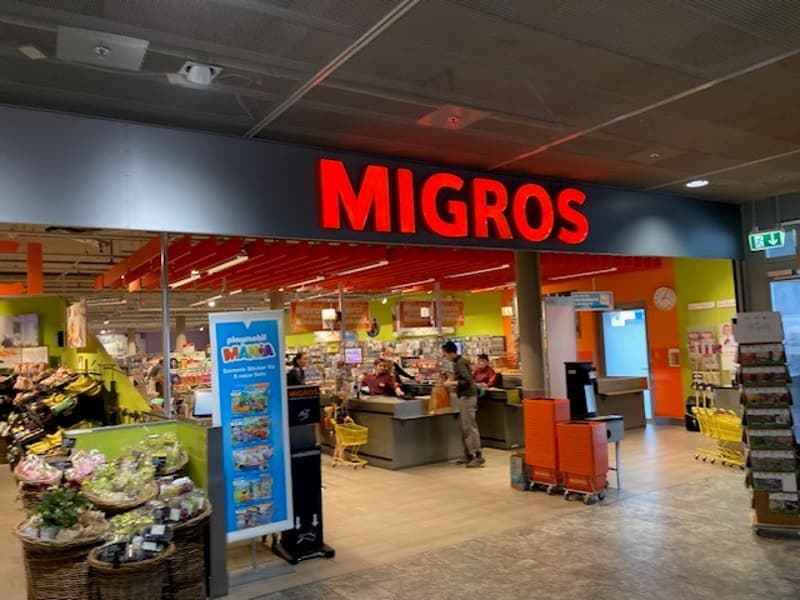 Grocery store entrance with baskets of fruit, groceries, check out area