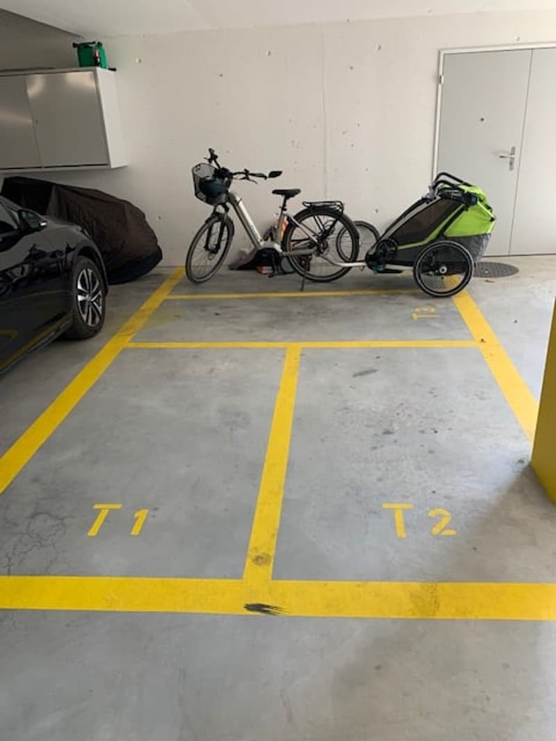Garage with designated parking spaces, a car, and a bicycle with a trailer attached