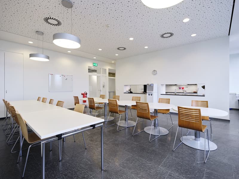 modern room with tables, chairs, tiled floor, hanging lamps, whiteboard, exit sign