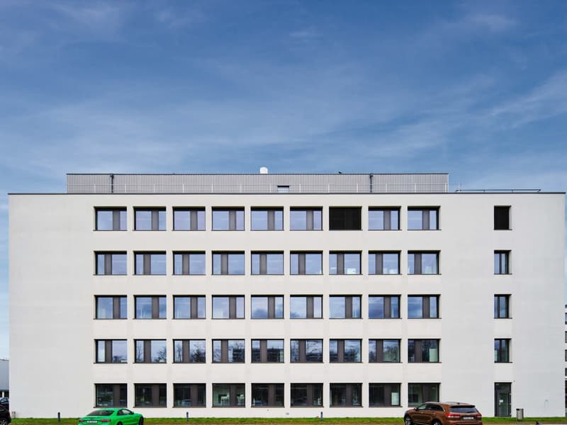 4 story office building, modern style, white facade, large windows, two cars parked in front