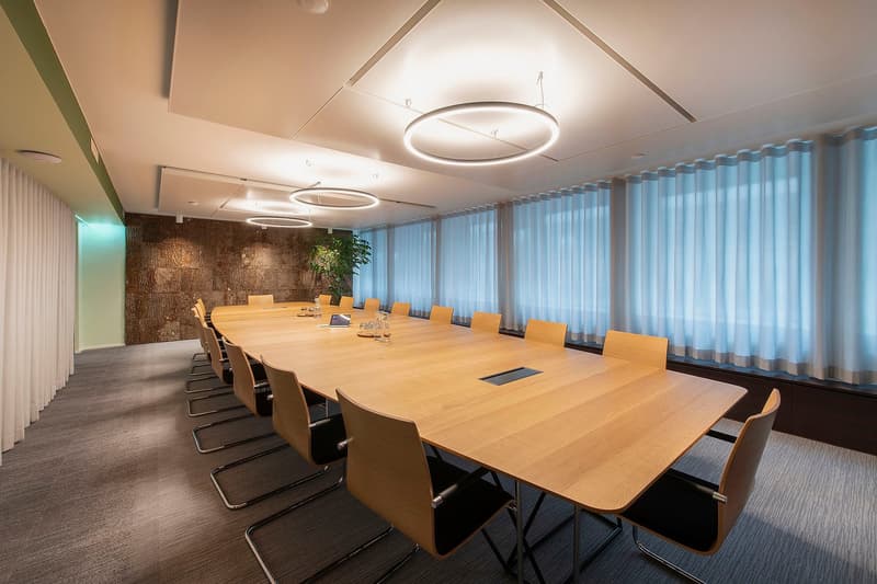 boardroom with long wooden table, modern chairs, and white drapes