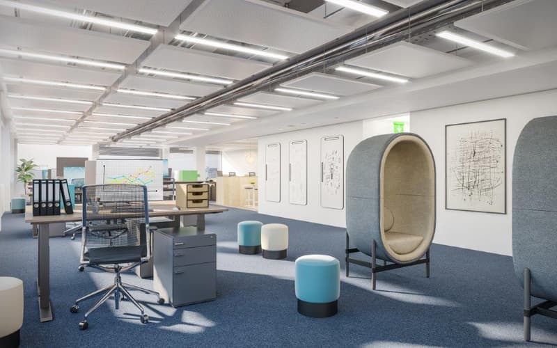 modern office layout with desks, chairs, and small seating pods, white walls, mounted picture frames, carpeted floor