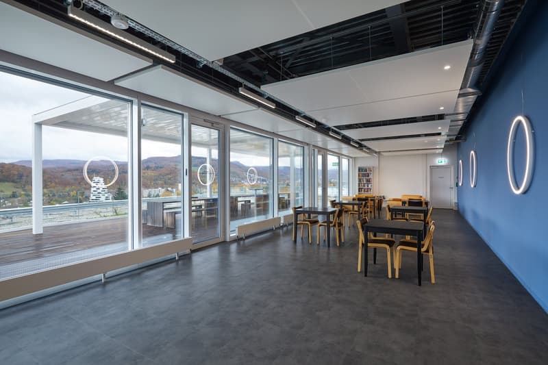 modern interior, large windows, tables and chairs, bookshelves, tiled floor, ceiling lights