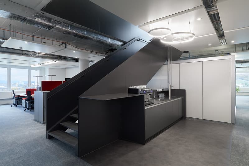 modern office space, black staircase, black countertops, white cabinets, large windows, office chairs, desks