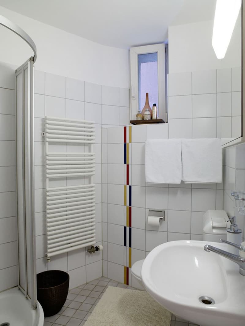 Bathroom with shower, sink, toilet, towel rack, radiator, small basket