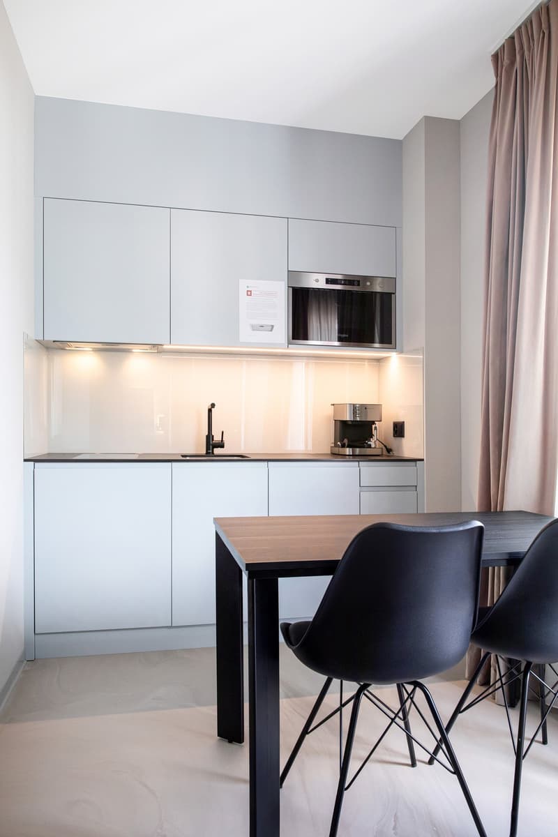 white cabinetry, wooden countertop, black chairs, sink, electric kettle, microwave