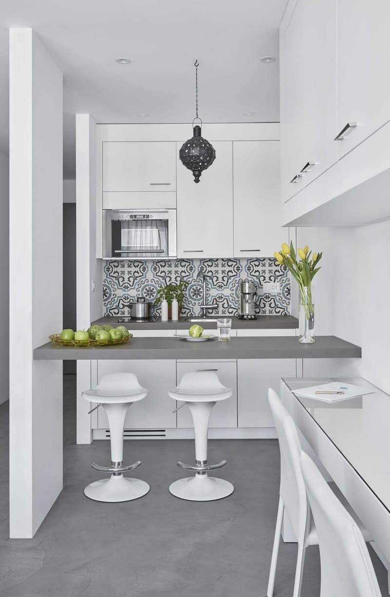 modern kitchen with white cabinets, gray countertop, pendant light, microwave, coffee machine, yellow flowers, green apples