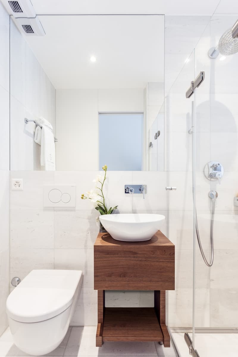 modern bathroom with white marble floor, glass shower enclosure, white sink, white toilet