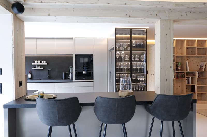 modern kitchen, gray bar stools, black countertops, white cabinets, open shelving for wine glasses