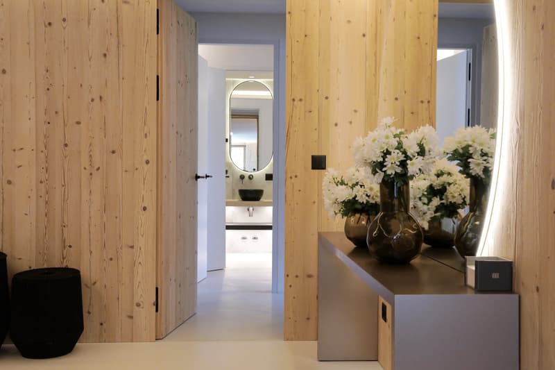 wooden walls, white floors, white flowers in vase, black trash cans, mirror